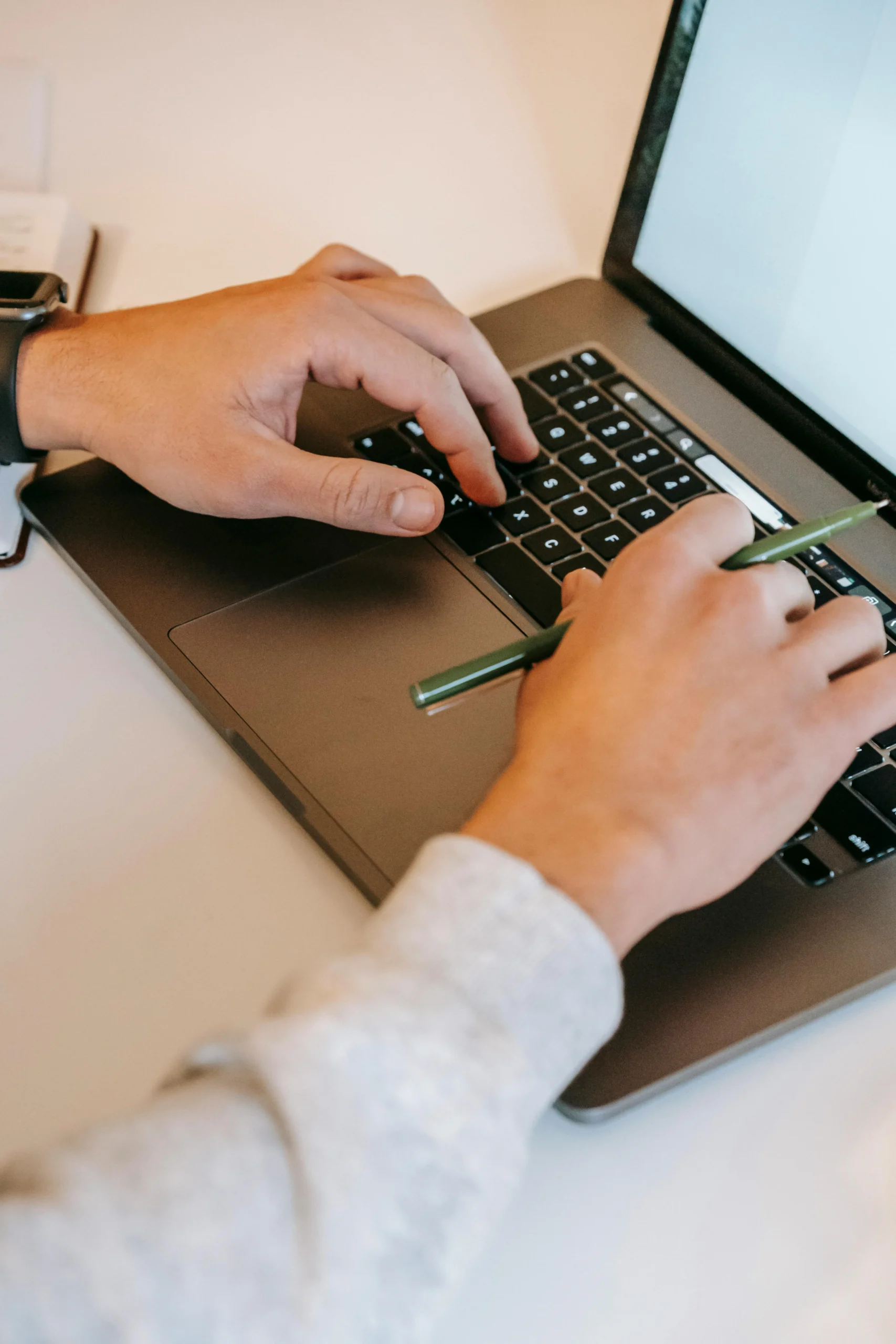 From above of crop unrecognizable freelancer sitting at white table and working on laptop at home